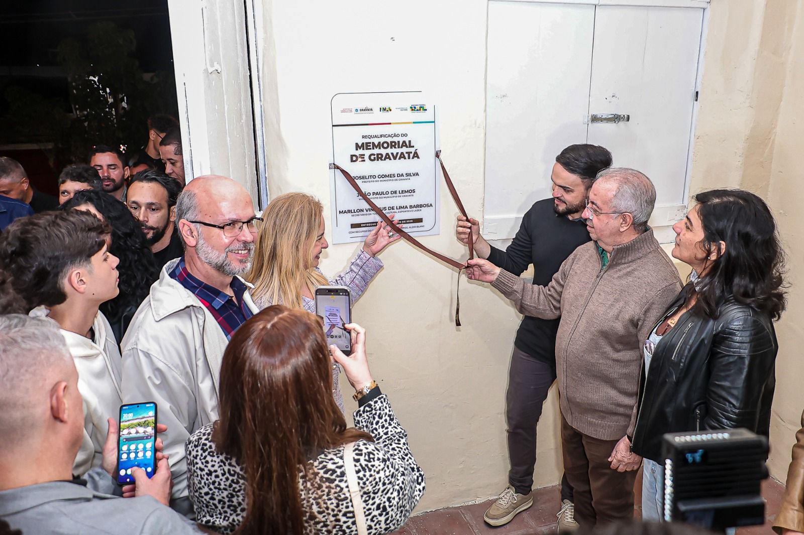 Grupo de pessoas participa da cerimônia de requalificação do Memorial de Gravatá. A placa de inauguração está sendo descerrada por autoridades locais.