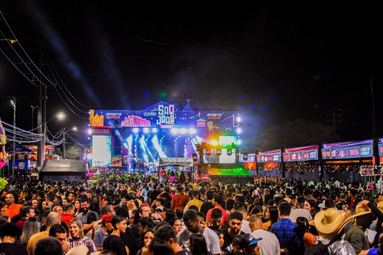 Multidão em frente a palco iluminado durante o São João de Gravatá.