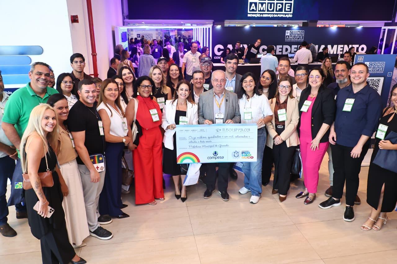 Equipe da Prefeitura de Gravatá posa com cheque simbólico de R$ 11,5 milhões destinado a obras hídricas e saneamento, durante Congresso da Amupe.