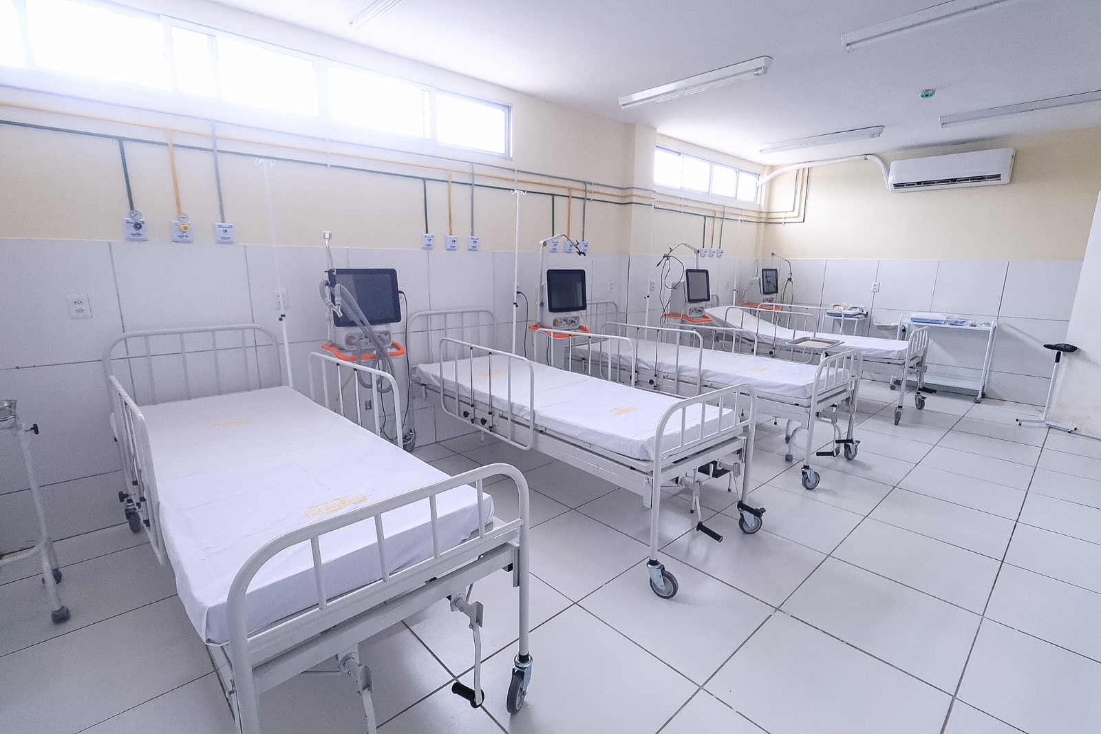 Enfermaria hospitalar com camas alinhadas e equipamentos médicos prontos para uso.