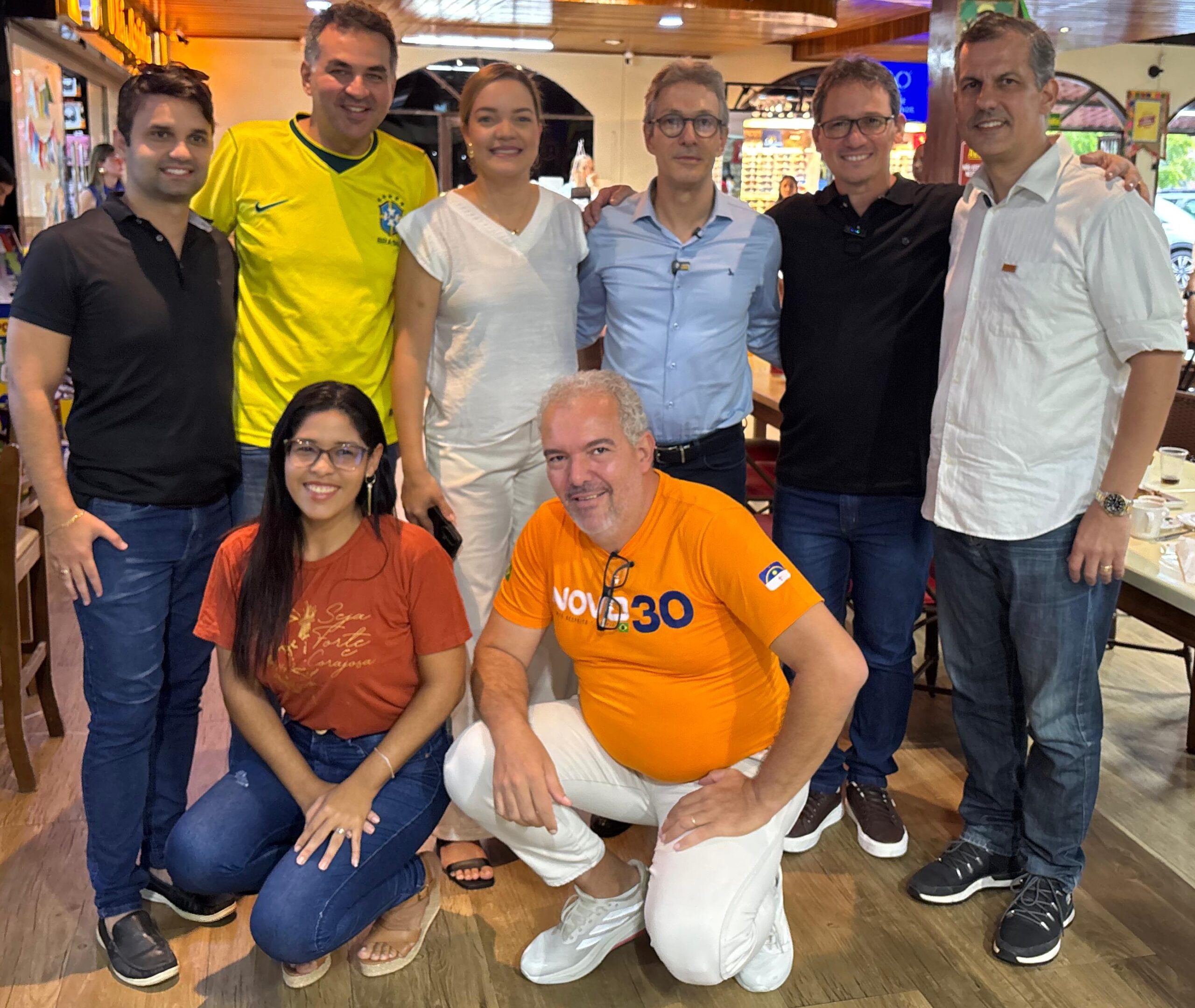 Fotografia de um grupo de nove pessoas posando em um restaurante. Ao centro da fileira de trás está Romeu Zema, pré-candidato à Presidência da República, vestindo camisa social azul-clara e óculos. À sua direita aparece Rodolfo Silva, pré-candidato a deputado estadual, usando camisa polo preta e óculos. Ao lado direito de Rodolfo está Carlos Sant’Ana, pré-candidato ao Senado, de camisa branca.